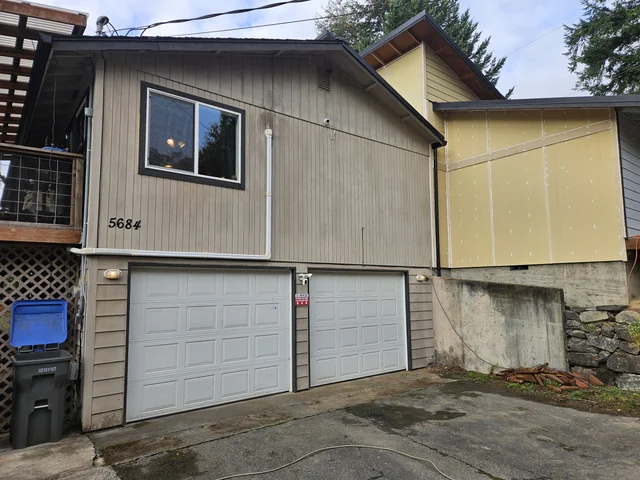 Port Orchard home's front exterior at an earlier stage, with beige and yellow surfaces and white trim.
